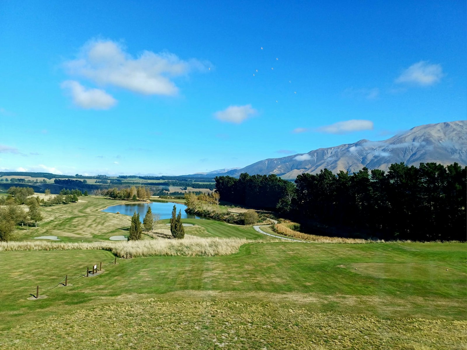Mountain golf course fairway with lake and distant ridgelines